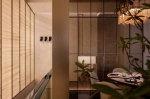 Interior of a minimalist restaurant featuring glass walls and a modern dining setup.