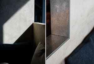 A modern industrial interior design featuring a concrete corner with a metal shelf.