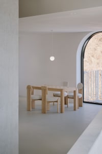 A modern interior space featuring four-legged wooden furniture with cushioned seats and a checkered wooden table.