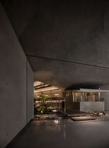 An industrial-style interior design featuring concrete walls and a courtyard with plants and stones.
