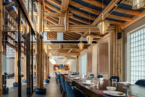 Modern restaurant interior with bamboo ceiling, glass walls, and wooden furniture.