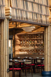Interior view of a restaurant and bar featuring bamboo walls and ceiling with modern lighting.