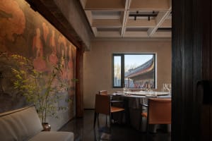 Modern, minimalist restaurant interior with concrete walls and a view through a window