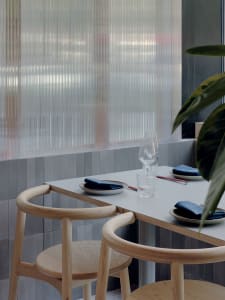 A modern restaurant interior with wooden tables and chairs.