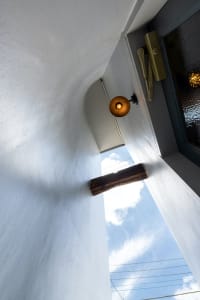 A minimalist interior space featuring a window with a wooden frame and a warm light bulb.