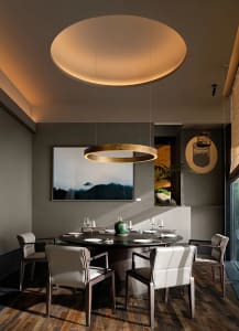 Modern dining room with wooden furniture, circular light fixture, and mountain art