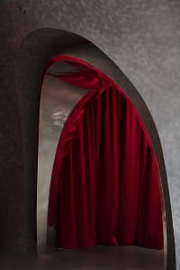 A modern architectural space featuring a red curtain draped over a curved wall.