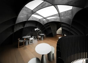 Modern industrial coffee shop interior with concrete walls and ceiling, multiple seating areas, and large skylights.