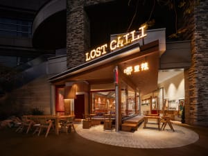 A restaurant's exterior with brick walls and a concrete floor, illuminated by neon signage.