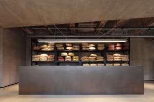 Industrial-style bakery interior with concrete counter displaying bags of flour and other baking ingredients.