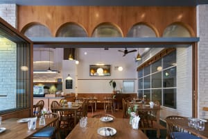 A modern restaurant interior with wooden furniture and brick walls.