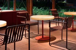 Outdoor café seating area with metallic furniture and red table tops.
