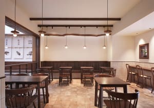 A modern restaurant interior with wooden furniture and tiled flooring.