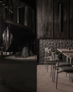Modern restaurant interior with black walls, steel elements, and concrete floor.