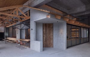A modern restaurant with exposed concrete walls and wooden accents.