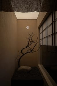 A minimalist corridor featuring concrete walls, stone flooring, and gravel accents.