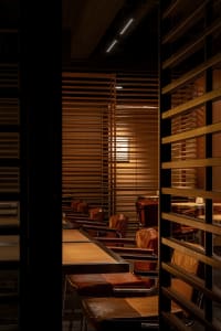 A row of brown leather restaurant seating with wood tables and metal legs.