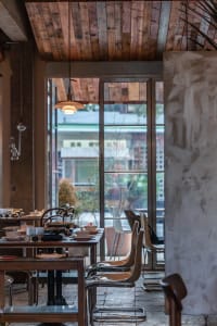 A stylish dining area with wooden furniture and large windows, offering a cozy and contemporary atmosphere.