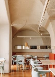 An empty minimalist restaurant interior with concrete walls and wooden floor.