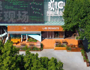 An outdoor seating area of a modern coffee shop with concrete walls and a terracotta facade.