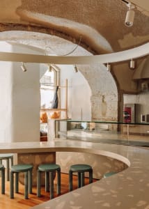 Minimalist coffee shop with terrazzo counter and green stools