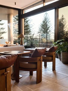 Modern lounge area with wooden furniture, concrete walls, and leather cushions in a restaurant setting.