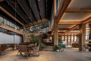 Industrial-style coffee shop interior with wood tables, chairs, and concrete flooring.