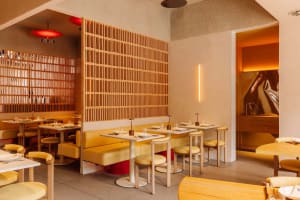 Modern minimalist restaurant interior with sleek, yellow furniture, and contemporary design features.