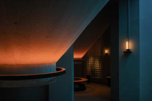 A modern lobby interior featuring exposed concrete walls and a warm, rugged lighting ambiance.