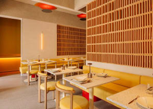 Modern restaurant interior featuring yellow seating, wooden accents, and concrete flooring