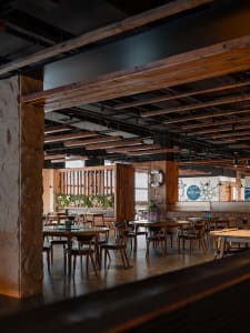 Industrially styled restaurant interior with wooden tables, chairs, and stone pillars