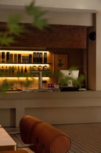 An industrial-style bar counter with metallic finishes and illuminated shelves.