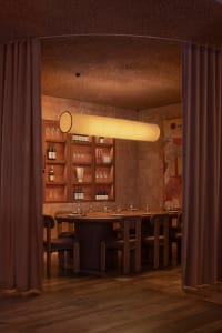Industrial-themed restaurant dining room featuring wooden seating, exposed brick walls, and a circular light fixture.