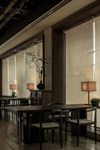 A modern cafe interior featuring wooden furniture, fabric seating, and metal accents.