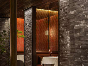 A cozy restaurant setting with brick walls, featuring a booth with a tablecloth and wine glass.