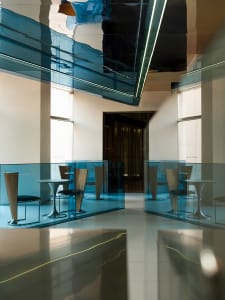 A modern office interior featuring glass walls and metal furniture.