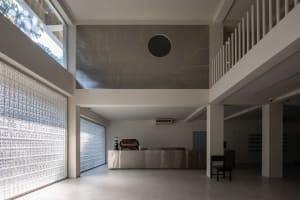 A minimalist coffee shop interior featuring a metal counter and glass walls.