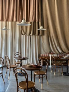 Industrially designed cafe interior featuring wooden tables, fabric curtains, and metal accents