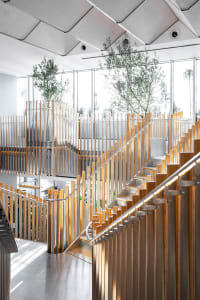 Staircase with metal and wooden railings, featuring modern-industrial design elements within an office setting.