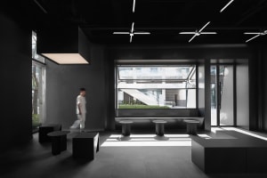 Minimalist commercial interior with metal elements and black tables and stools.