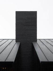 Modern black metal roof structure with seamless metal roofing panels.