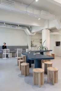 Interior view of a modern restaurant featuring minimalist design with concrete, wood, and metal elements.