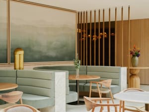 A modern restaurant interior with booth seating upholstered in suede and accented with marble and wood.