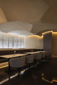 Modern restaurant interior featuring marble and concrete materials, designed to create a sophisticated atmosphere.