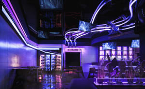 An industrial-style bar interior with neon lighting, concrete walls, and a warm, welcoming atmosphere.