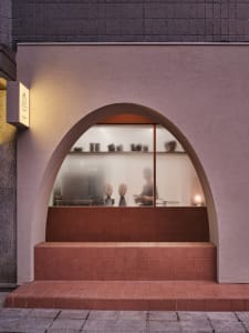 The minimalist interior of a coffee shop featuring concrete floors and glass walls.