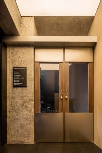 A modern entryway featuring wooden and concrete doors with glass windows.