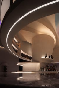 A modern bar interior with concrete elements and illuminated shelves.