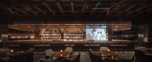 Modern metallic bar interior with arches and a large projection screen.