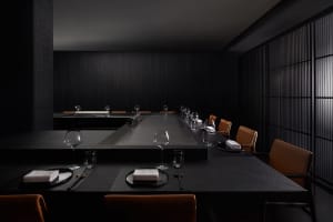 A modern restaurant interior featuring a sleek black stone dining area with minimalist decor and elegant table settings.